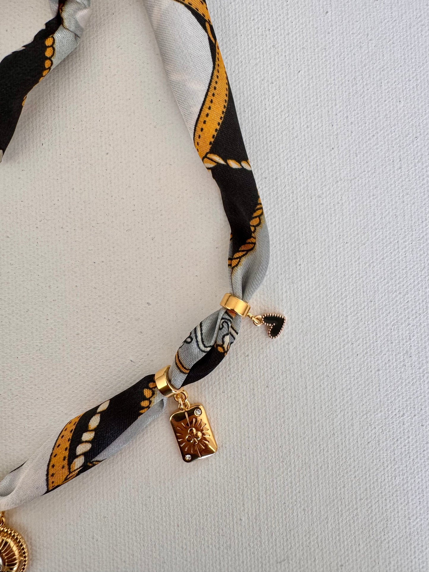 Charm-Bandana mit goldenen Anhängern in Schwarz-Gold-Mix • Statement-Accessoire mit Herz-, Sonne- & Kristall-Details